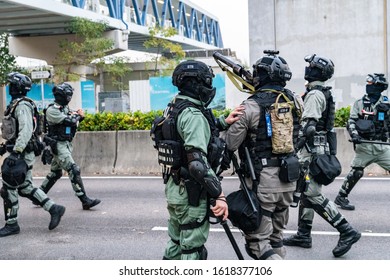 HONG KONG - DECEMBER 22 2019: A Hong Kong Riot Police Officer Points A Tear Gas Gun At Members Of Public Walking On A Bridge At The IFC Mall In Central Hong Kong.