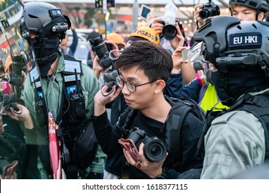 HONG KONG - DECEMBER 22 2019: A member of the press is pinned up against a car and searched by riot police following a rally at Edinburgh Place, central Hong Kong.