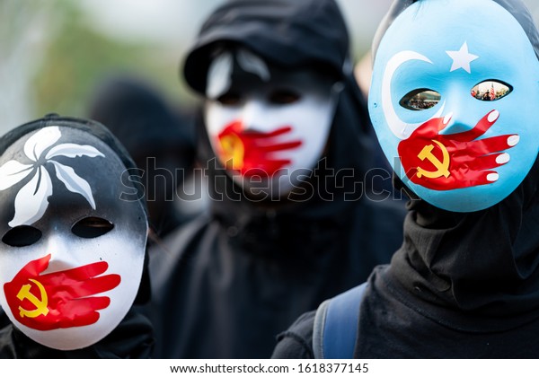 HONG KONG - DECEMBER 22 2019: A group of protestors\
wear masks symbolizing the Communist Party of China\'s silencing of\
Uyghur Muslims and the Hong Kong pro-democracy movement at a rally\
in Hong Kong.