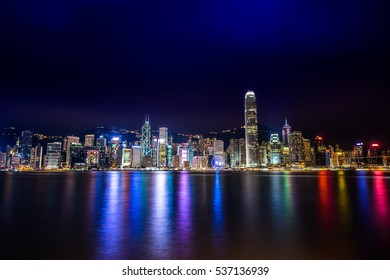 Hong Kong Harbour By Night In Long Exposure Mode. Colorful Skyscrapers Financial Districts. Night Scene With Neon Lightings