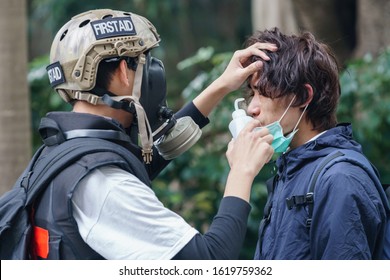 HONG KONG - JANUARY 19 2020: A volunteer first aid officer assists an injured man after riot police fired tear gas at a crowd to disperse them during the 'Universal Siege on Communists' rally.