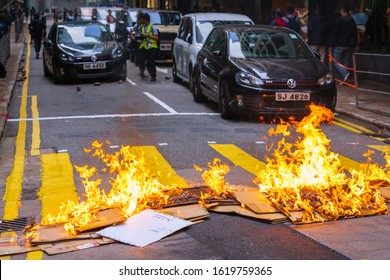 HONG KONG - JANUARY 19 2020: A fire set by frontline protesters blocks traffic on a street in the central business district of Hong Kong following a nearby rally.
