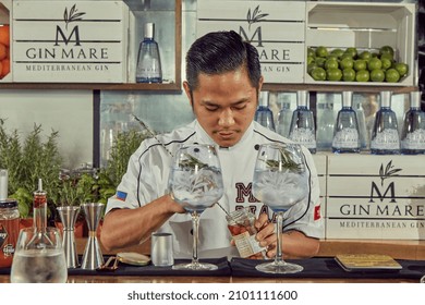 HONG KONG, SAR CHINA, AUGUST 2017: Young Asian Bartender Preparing His Gin And Tonic With GinMare Spanish Gin, Adding The Last Part Of The Garnish To The Drinks