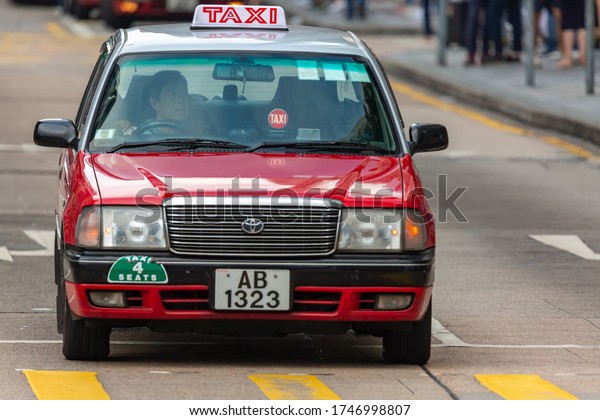 Hong Kong, SAR China - May, 2019: Typical Hong Kong\
red taxi car. Red Toyota Crown Comfort cars in a city street Nathan\
Road.