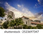 Honolulu City Hall with lush green palm trees and plants and powerful clouds at sunset in downtown Honolulu Hawaii USA