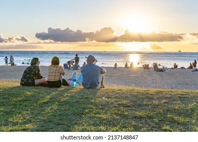 Honolulu, Hawaii - circa February 2022: Friends enjoy watching the sunset at at Ala Moana Beach Park.