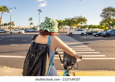 Honolulu, Hawaii - circa February 2022: A woman rides a bike toward Ala Moana Beach Park.