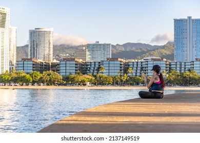 Honolulu, Hawaii - circa February 2022: A woman relaxes at Ala Moana Beach Park, with the city skyline in the distance.