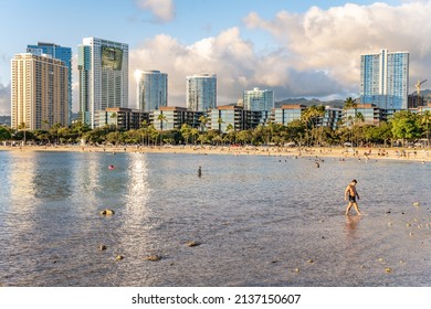 Honolulu, Hawaii - circa February 2022: People enjoy a relaxing day at Ala Moana Beach Park, with the city skyline beyond.
