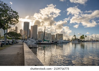 Honolulu, Hawaii - circa February 2022: The city skyline in view beyond a pedestrian path along the water at Ala Moana harbor. 