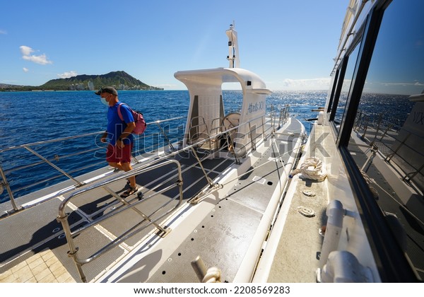 Honolulu,\
Hawaii - February 10, 2022 : Tourist unboarding a submarine on the\
upper deck of a submersible ship moored to a boat in front of\
Diamond Head mountain in Honolulu,\
Hawaii