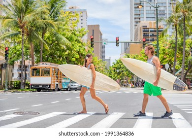 Honolulu Hawaii surfers couple tourists people walking crossing city street carrying surfboards going to the beach surfing. Surf living lifestyle. Surfer woman and man friends in Waikiki, Oahu, USA. - Powered by Shutterstock