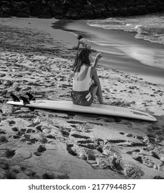 Honolulu, Hawaii, USA.  July 13,  2022.  A Surfer Girl Sitting On The Wand Preparing To Surf Waikiki.