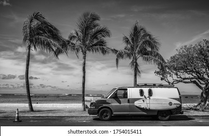 Honolulu, Hawaii, USA.  June 11, 2020.  Vintage Surfing Van With Surfboard On A Side Rack With Palm Trees And Surf In The Background.