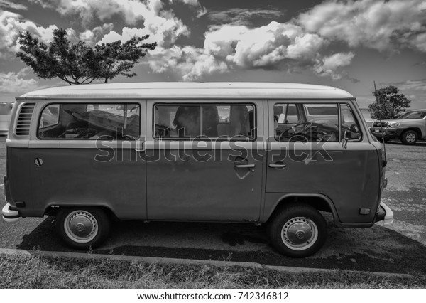 Honolulu, Hawaii, USA, Oct. 26, 2017: \
Monochrome beach side photograph of a 1968 Surfing Van parked at\
Ala Moana Beach Park with ocean and sky background.\
