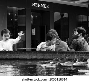 Honolulu, Hawaii, USA.  October 9, 2021.  Young children watching Koi in a fish pond at Ala Moana Center.