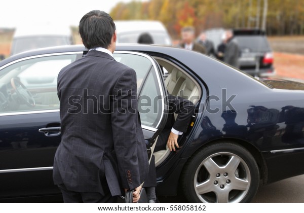 Honorable businessman out of the car with the\
help of his assistant.\
Coming investor ceremony of laying of the\
new place of investment. Unrecognizable person. Business investment\
concept.