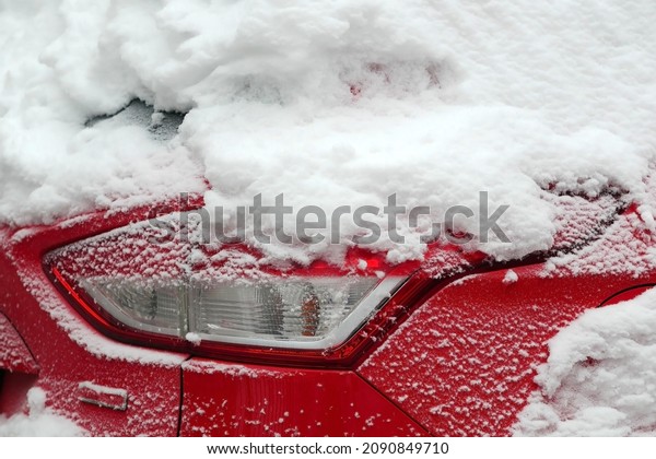 Hood red metal car\
with headlight in the snow close up, Light passenger car luxury\
class under snow cover.