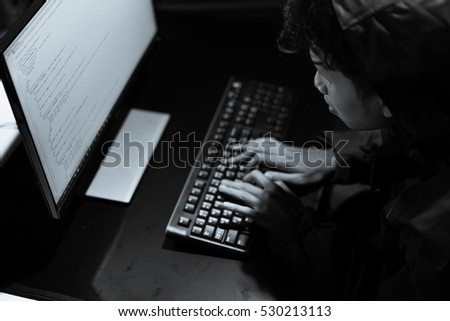 Hooded computer hacker stealing information with laptop