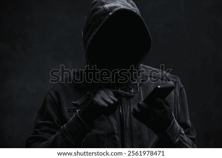 Hooded computer hacker using smartphone, selective focus