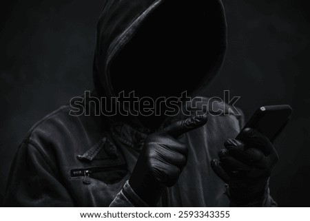 Hooded computer hacker using smartphone, selective focus