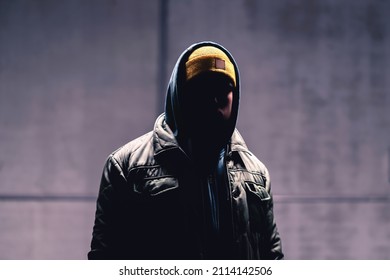 Hooded criminal in dark. Mystery man with hood. Gangster in urban street. Hooligan in hoodie. Stalker with hidden face. Unknown suspicious thief, burglar, hacker or terrorist with grunge background. - Shutterstock ID 2114142506