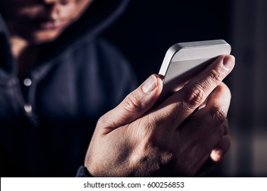 Hooded cyber crime hacker using mobile phone internet hacking in to cyberspace,online personal data security concept