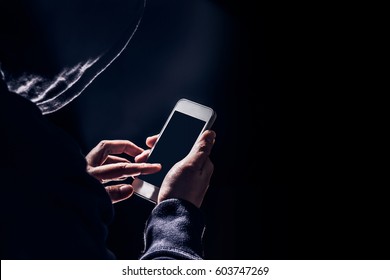 Hooded cyber crime hacker using mobile phone internet hacking in to cyberspace,online personal data security concept.