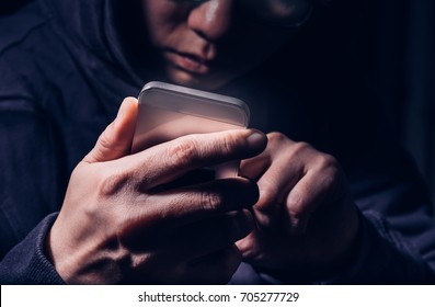 Hooded Cyber Crime Hacker Using Mobile Phone Internet Hacking In To Cyberspace,online Personal Data Security Concept.