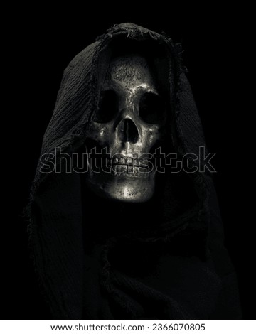 Hooded Grim Reaper figure emerging from the shadows. Terrifying human skull, haunted spirt, or frightening ghost rising from dead.