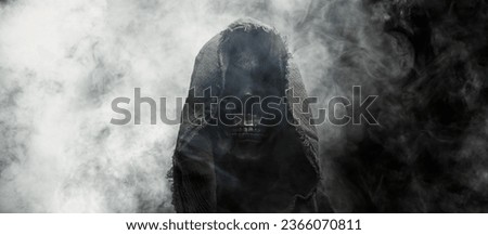 Hooded Grim Reaper figure emerging from the fog. Terrifying human skull, haunted spirt, or frightening ghost rising from dead.
