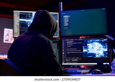 Hooded hacker coding on PC, using AI to evade security with stealth malware. Evil man using artificial intelligence script on computer to hide malicious code from detection systems
