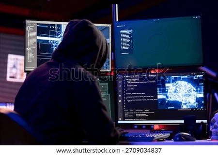 Hooded hacker coding on PC, using AI to evade security with stealth malware. Evil man using artificial intelligence script on computer to hide malicious code from detection systems