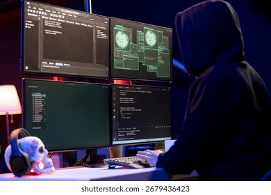 Hooded hacker in underground HQ coding malware designed to exploit network backdoors, Rogue programmer bypassing security measures such as logins and password protections