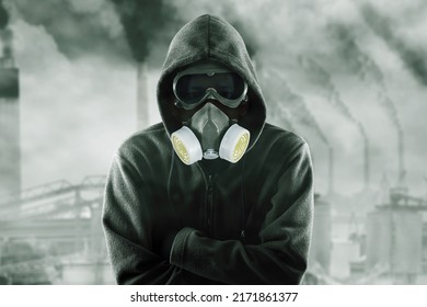 Hooded man wearing gas mask while standing with confident expression in the polluted city