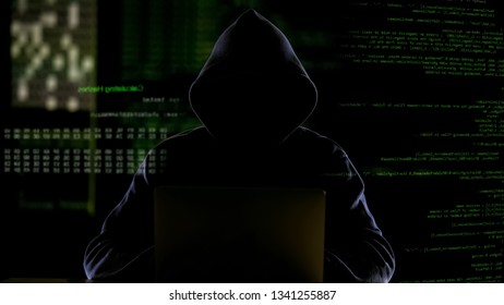 Hooded man working with computer code, hacking software, stealing private data