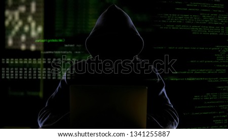 Hooded man working with computer code, hacking software, stealing private data