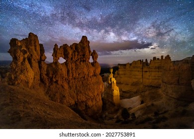 A hoodoo with small windows and Thor's Hammer against a night sky with clouds and the Milky Way below Sunset Point in ryce Canyon National Park, Utah. - Powered by Shutterstock