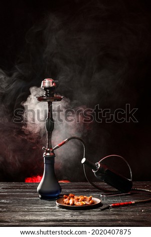 Hookah, bottle of wine and dates on table