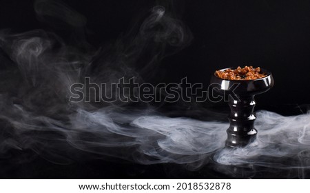 hookah bowl with tobacco on a black background with smoke. space for text