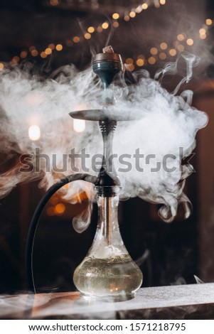 
Hookah with a clear liquid on the table and a lot of smoke around