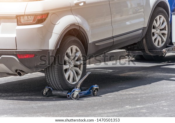 Hooked up\
car on a tow truck on a roadside, close up view of the rear wheel\
of a car and a transportation\
platform