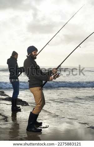 Hooking the big one. two young men fishing at the ocean in the early morning.