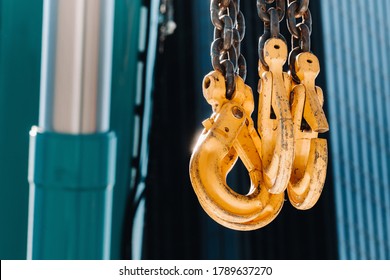 The hooks of the mobile crane near the glass of high buildings.Lots of hooks hanging from chains suspended from a crane