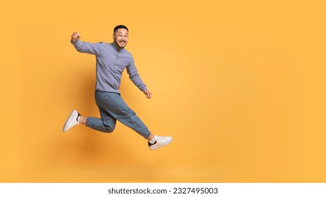 Hooray. Overjoyed Young Asian Guy Jumping In Air Over Yellow Background In Studio, Happy Cheerful Millennial Man Having Fun, Shouting Yes, Expressing Positive Emotions, Panorama With Copy Space