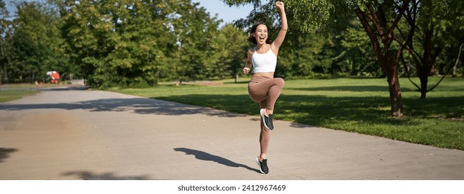 Hooray, victory. Smiling asian girl triumphing, celebrating achievement, running till finish, shouting from excitement. - Powered by Shutterstock