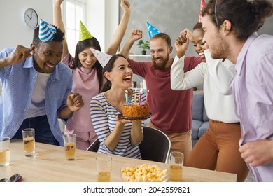 Hooray, you turned twenty today. Diverse multiracial group of excited friends giving a cake to a happy young woman at her birthday party at home. Young woman in her 20s getting presents and having fun - Powered by Shutterstock