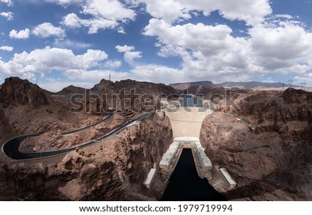 The Hoover Dam is seen from the Mike O'Callaghan - Pat Tillman Memorial Bridge (Hoover Dam Bypass). Panorama photo with clouds, wide angle. 