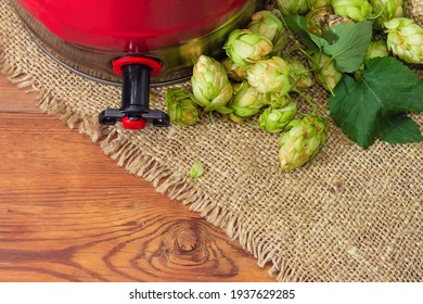 Hop Cones And Fragment Of Bottom Part Of Disposable Beer Mini Keg With Built-in Beer Tap On Sackcloth On Rustic Table Close-up, Top View
