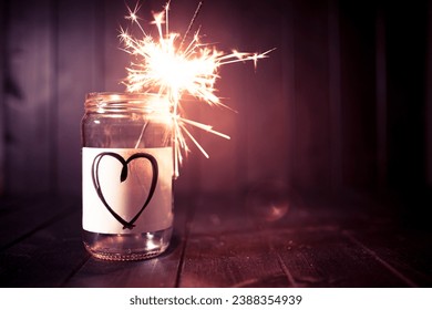 Hope for love, still life with glass jar with heart symbol and burning sparkler. Romantic pink tone. Background with copy space for Valentine.